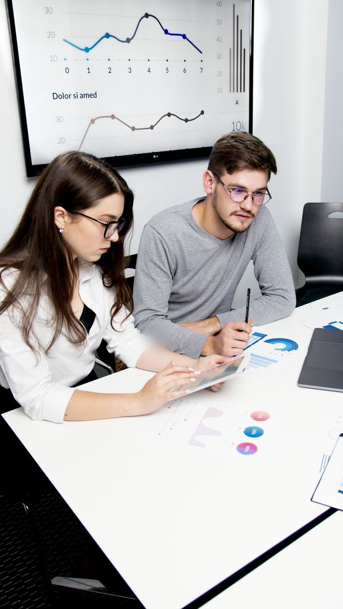 gallery-06 Two business professionals collaborating on financial analysis with charts and graphs.